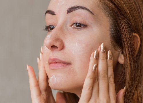 Woman applying face cream to treat acne