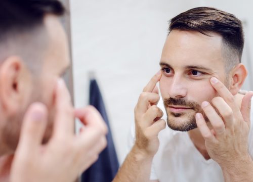 Man looking in the mirror to check for facial volume loss