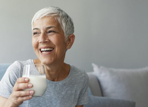 Happy older woman holding a glass of milk