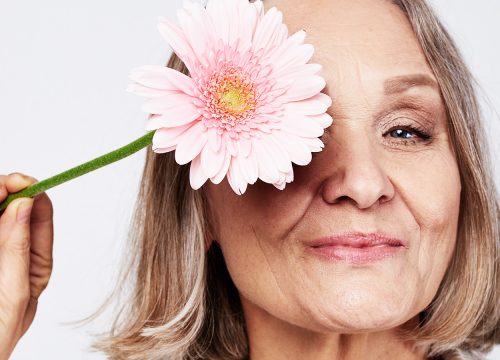 Older woman holding up a flower to her face