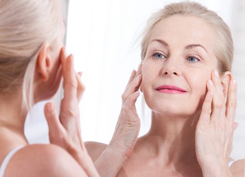Woman with wrinkles and fine lines looking in the mirror