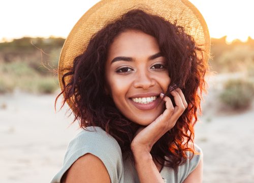 Woman wearing a hat smiling on a beach